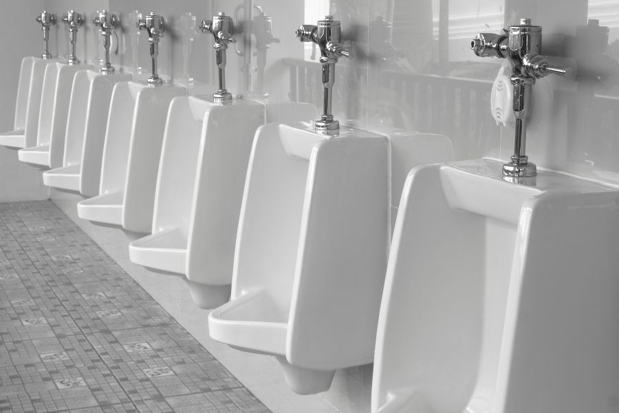 A Clean White Light Commercial Washroom with A Row of urinals