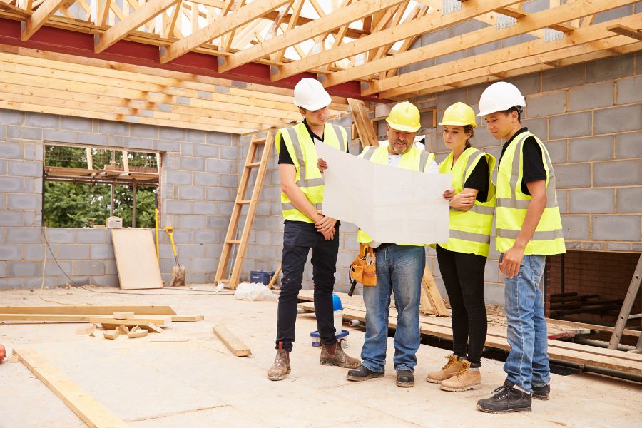 4 builders looking at plans in a newly constructed building
