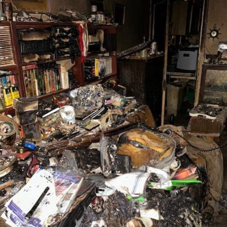 A living room piled high with damaged items after a devastating fire