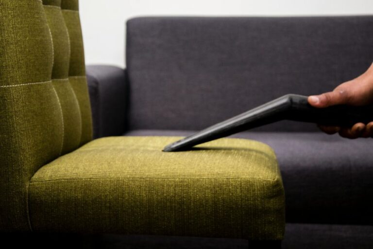 a green chair being cleaned and vacuumed in a living room with a sofa in the background
