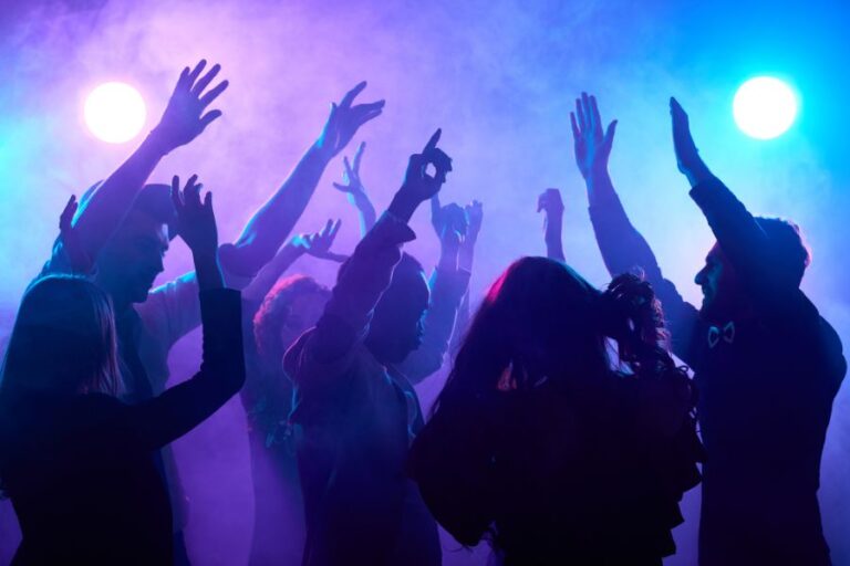 a group of adult silhouettes dancing in a nightclub rave