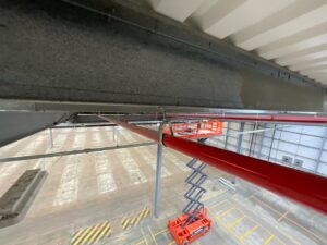 High level industrial cleaning of steel beams and pipework inside a warehouse using access platform