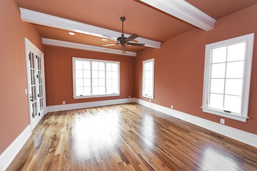 An empty room of a void property with terracotta coloured walls and wooden flooring