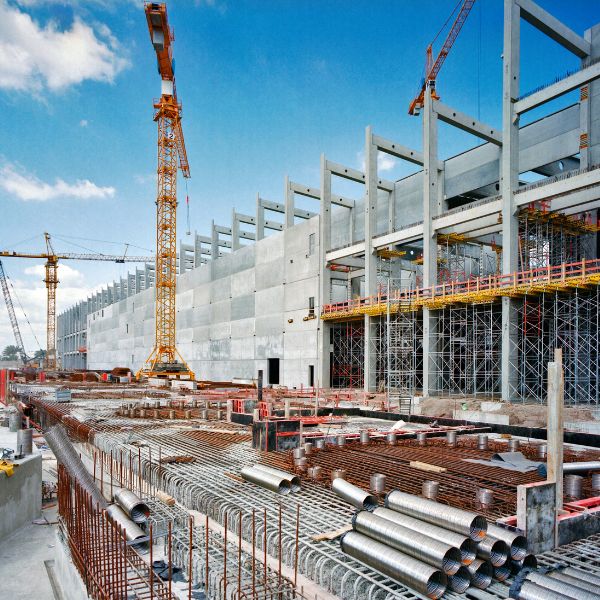 Large construction site with steel framework and groundwork preparation for commercial development