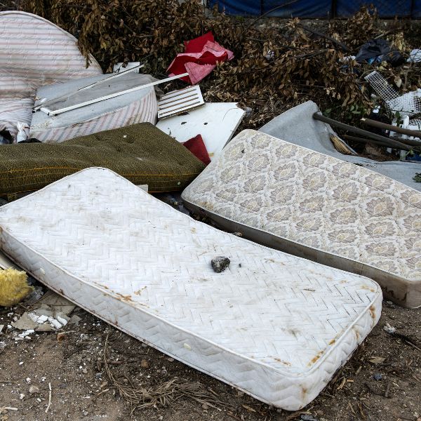 Fly tipped waste including discarded mattresses and household rubbish requiring specialist clearance
